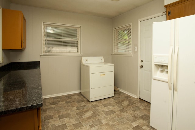 clothes washing area with cabinets, washer / dryer, and wooden walls