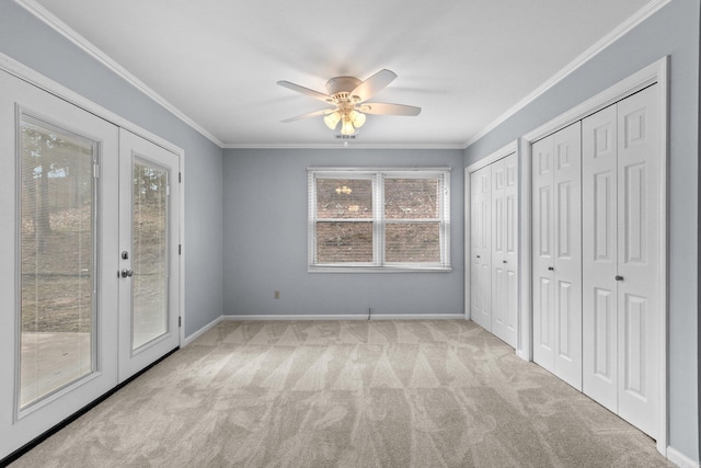 unfurnished bedroom with crown molding, access to exterior, two closets, light colored carpet, and french doors