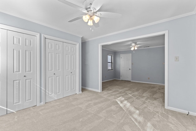 unfurnished bedroom with crown molding, two closets, light carpet, and ceiling fan