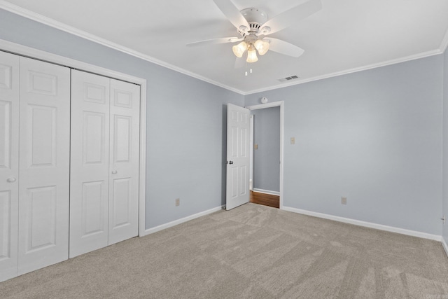 unfurnished bedroom featuring ornamental molding, light carpet, ceiling fan, and a closet