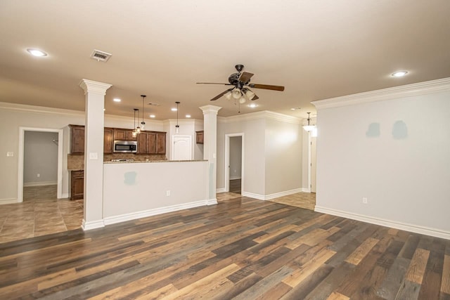 unfurnished living room featuring dark wood-type flooring, ceiling fan, and ornate columns