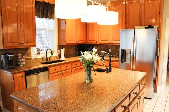 kitchen with appliances with stainless steel finishes, light stone countertops, sink, and backsplash