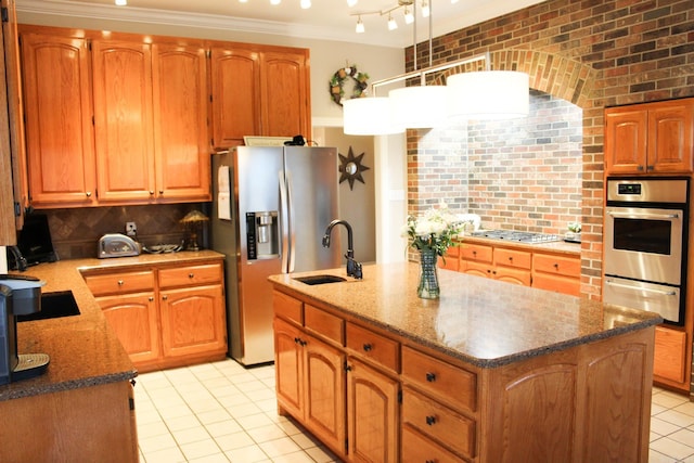 kitchen featuring brick wall, appliances with stainless steel finishes, sink, and a kitchen island with sink