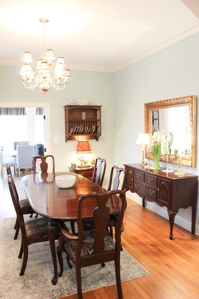 dining space featuring crown molding, an inviting chandelier, and light wood-type flooring