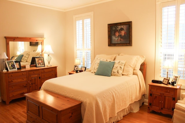 bedroom with ornamental molding and light hardwood / wood-style flooring