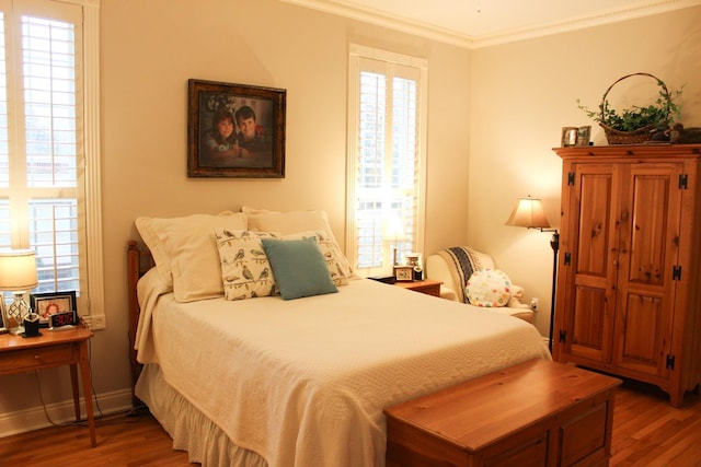 bedroom featuring ornamental molding, wood-type flooring, and multiple windows