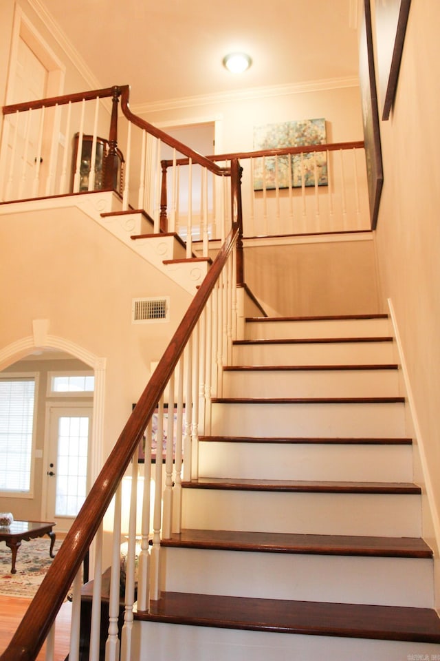 stairway with a towering ceiling and ornamental molding