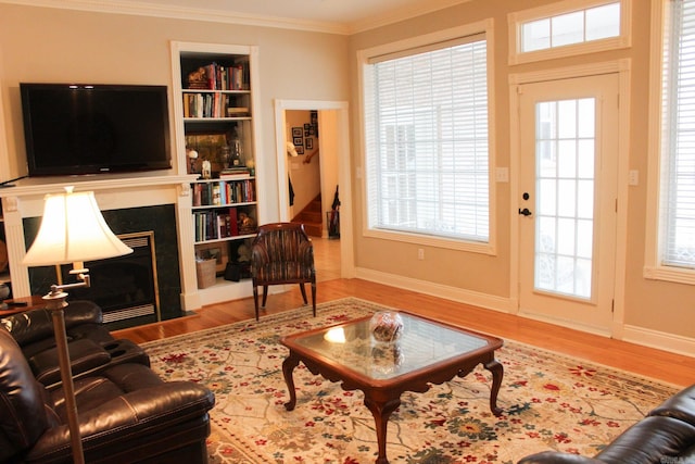 living room with built in features, wood-type flooring, and ornamental molding