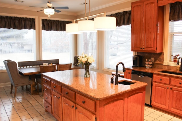 kitchen featuring crown molding, stainless steel dishwasher, sink, and a center island with sink