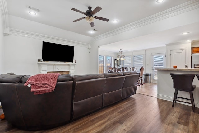 living room featuring dark hardwood / wood-style flooring, crown molding, and ceiling fan with notable chandelier