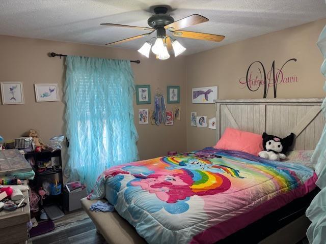 bedroom with ceiling fan, dark hardwood / wood-style flooring, and a textured ceiling