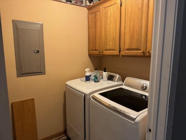 clothes washing area with cabinets, electric panel, and washer and dryer