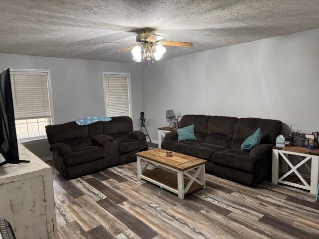 living room featuring ceiling fan, dark hardwood / wood-style floors, and a textured ceiling