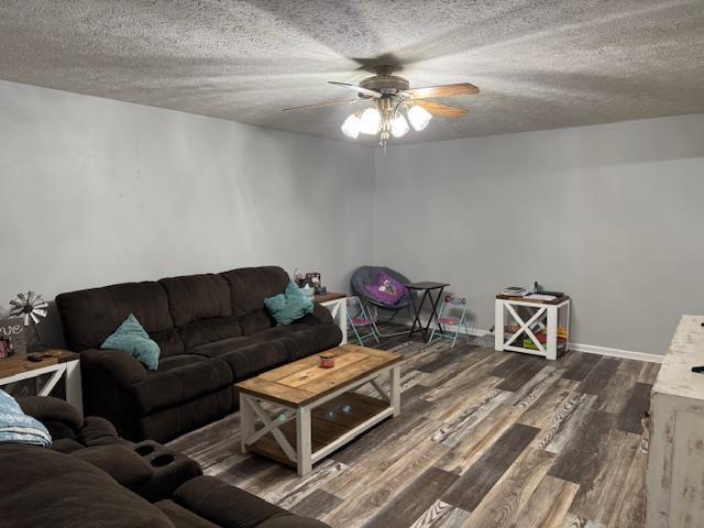 living room featuring ceiling fan, dark hardwood / wood-style floors, and a textured ceiling