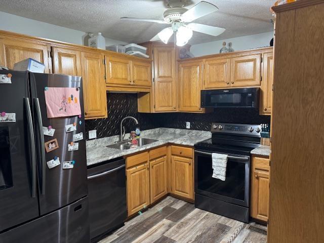 kitchen with sink, ceiling fan, dark hardwood / wood-style floors, black appliances, and a textured ceiling