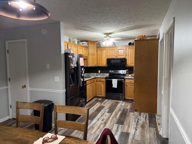 kitchen featuring ceiling fan, dark hardwood / wood-style flooring, a textured ceiling, and black appliances