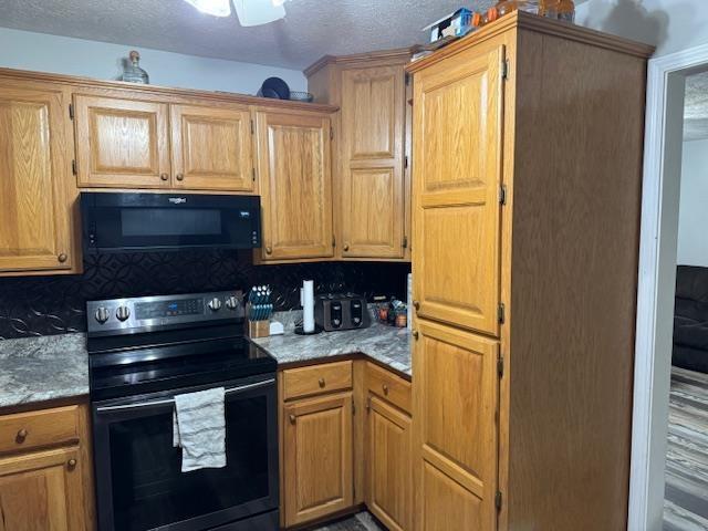 kitchen featuring tasteful backsplash, black appliances, and a textured ceiling