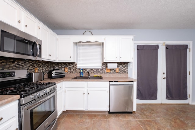 kitchen with stainless steel appliances, tasteful backsplash, sink, and white cabinets