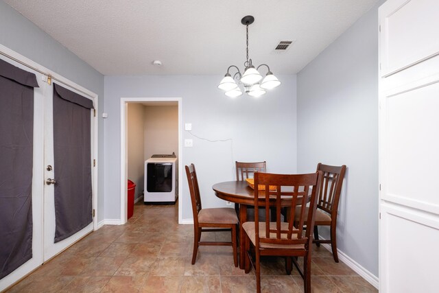 dining space featuring washer / clothes dryer, a textured ceiling, and a notable chandelier