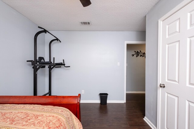 bedroom with dark wood-type flooring, ceiling fan, and a textured ceiling