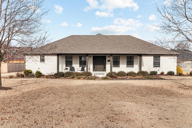 ranch-style home with brick siding, a porch, and roof with shingles