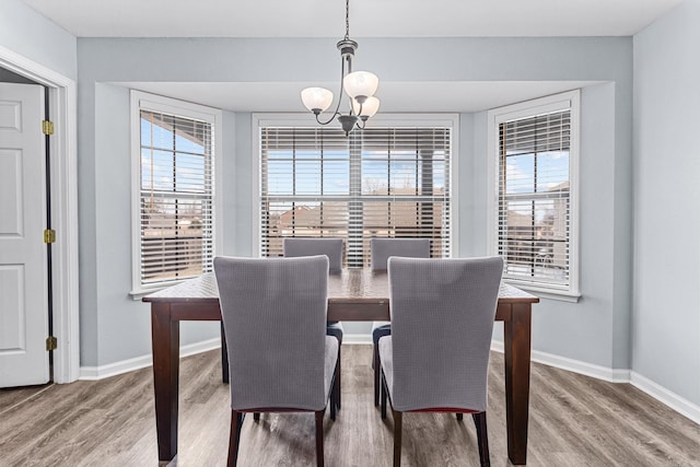 dining area with a notable chandelier, wood finished floors, baseboards, and a healthy amount of sunlight