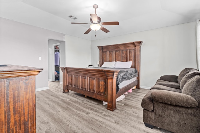 bedroom with visible vents, a ceiling fan, light wood-style floors, baseboards, and a spacious closet