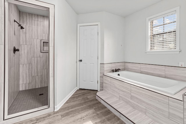 full bath with baseboards, tiled shower, a garden tub, and wood finished floors