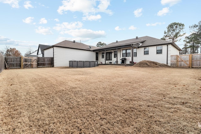 rear view of property with a fenced backyard and a gate