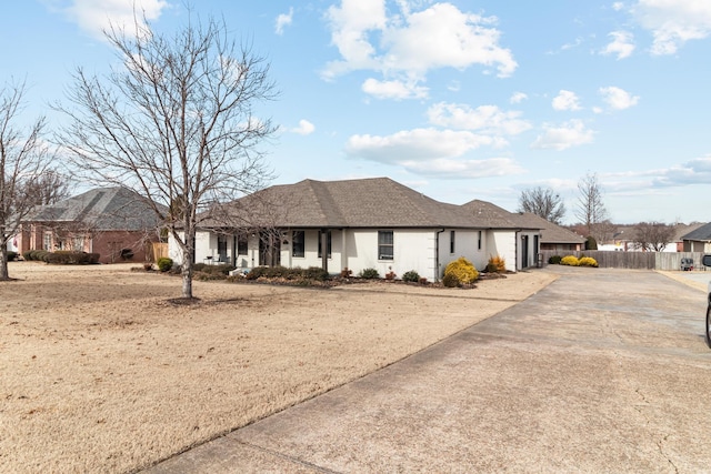 ranch-style home with a garage, a shingled roof, driveway, and fence