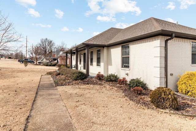 view of side of property with brick siding and roof with shingles