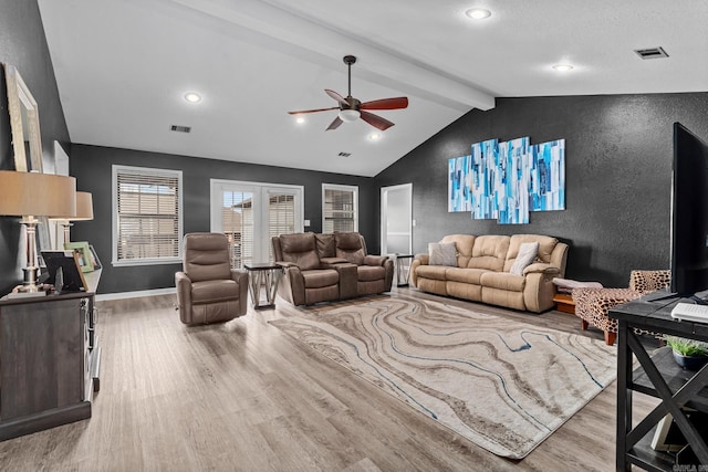 living area featuring visible vents, baseboards, wood finished floors, and vaulted ceiling with beams