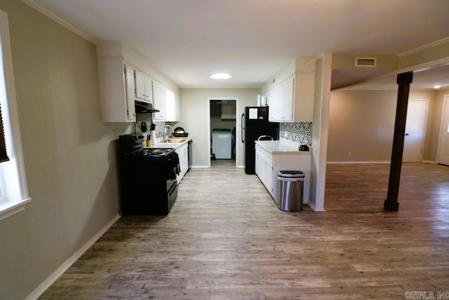 kitchen featuring backsplash, white cabinets, light hardwood / wood-style floors, and black appliances