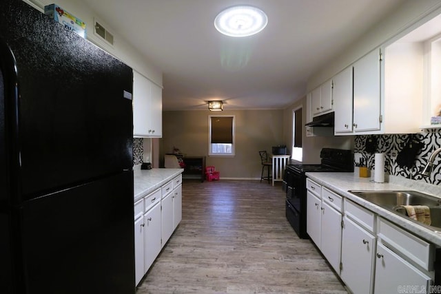 kitchen with white cabinetry, backsplash, light hardwood / wood-style floors, and black appliances