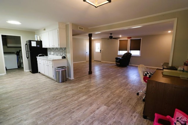 kitchen featuring light wood-type flooring, black refrigerator, white cabinets, washer / clothes dryer, and backsplash