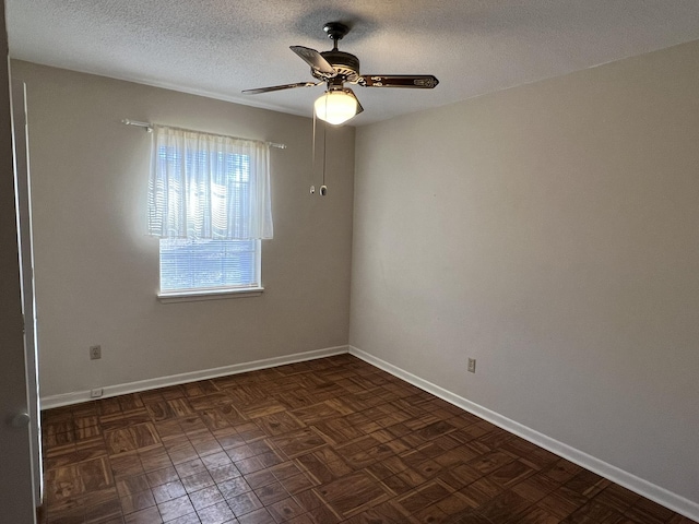 spare room featuring ceiling fan, dark parquet flooring, and a textured ceiling