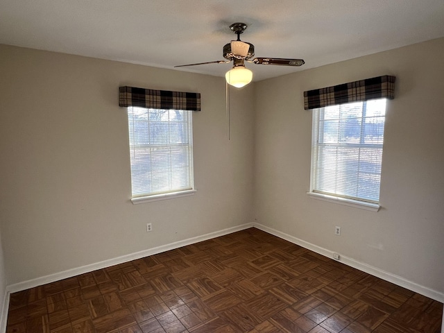 spare room featuring plenty of natural light, dark parquet floors, and ceiling fan