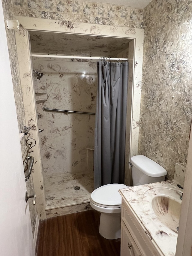 bathroom with hardwood / wood-style flooring, vanity, toilet, and walk in shower