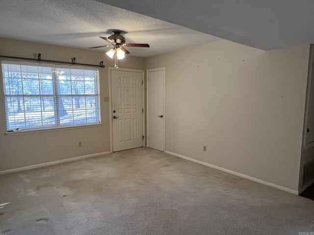 carpeted empty room featuring ceiling fan and a textured ceiling