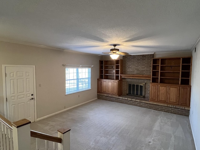 unfurnished living room with ceiling fan, crown molding, a brick fireplace, light carpet, and a textured ceiling