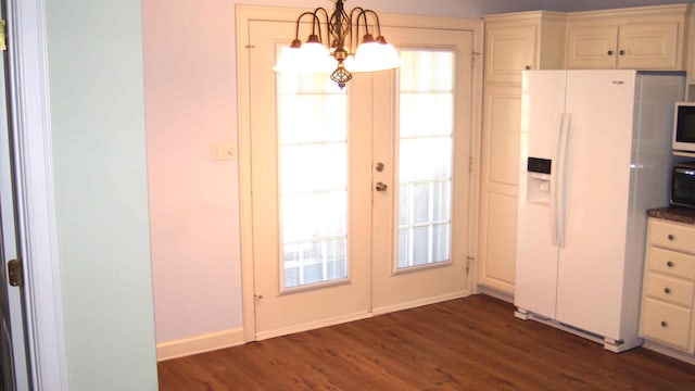 interior space with dark hardwood / wood-style floors, hanging light fixtures, white fridge with ice dispenser, an inviting chandelier, and french doors