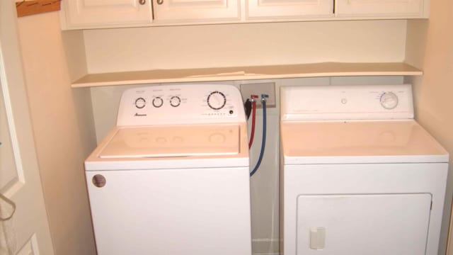 laundry area with washer and clothes dryer and cabinets