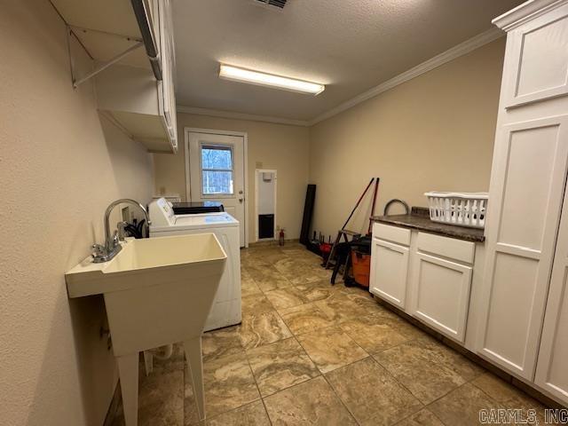 laundry area with ornamental molding, washer and clothes dryer, and sink