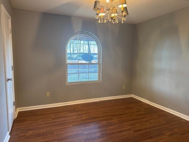 unfurnished room featuring dark wood-type flooring and a notable chandelier