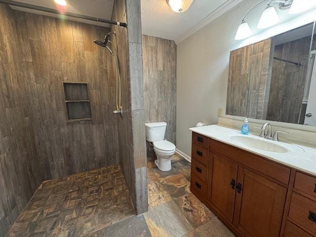 bathroom featuring tiled shower, vanity, toilet, and ornamental molding