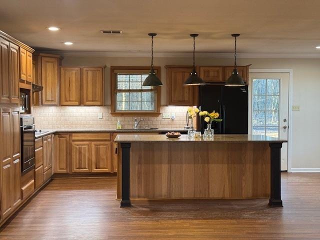 kitchen with wall oven, hanging light fixtures, a center island, and black fridge