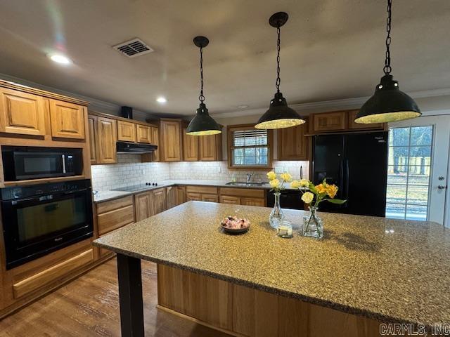 kitchen featuring light stone countertops, exhaust hood, decorative backsplash, and black appliances