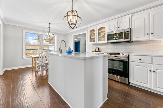 kitchen featuring appliances with stainless steel finishes, hanging light fixtures, white cabinets, a center island with sink, and a chandelier