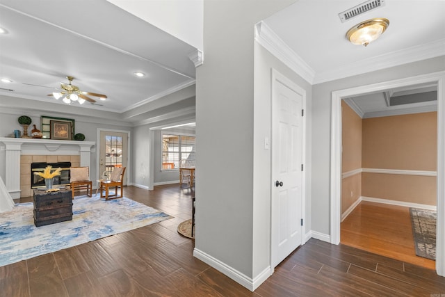 entrance foyer featuring a tiled fireplace, crown molding, and ceiling fan