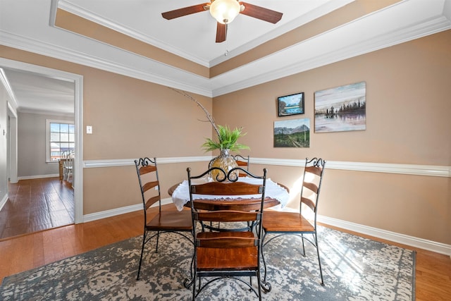 dining space featuring crown molding, hardwood / wood-style flooring, a raised ceiling, and ceiling fan